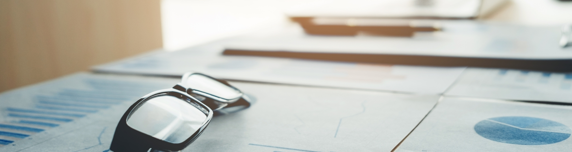 glasses on desk with paperwork and pen